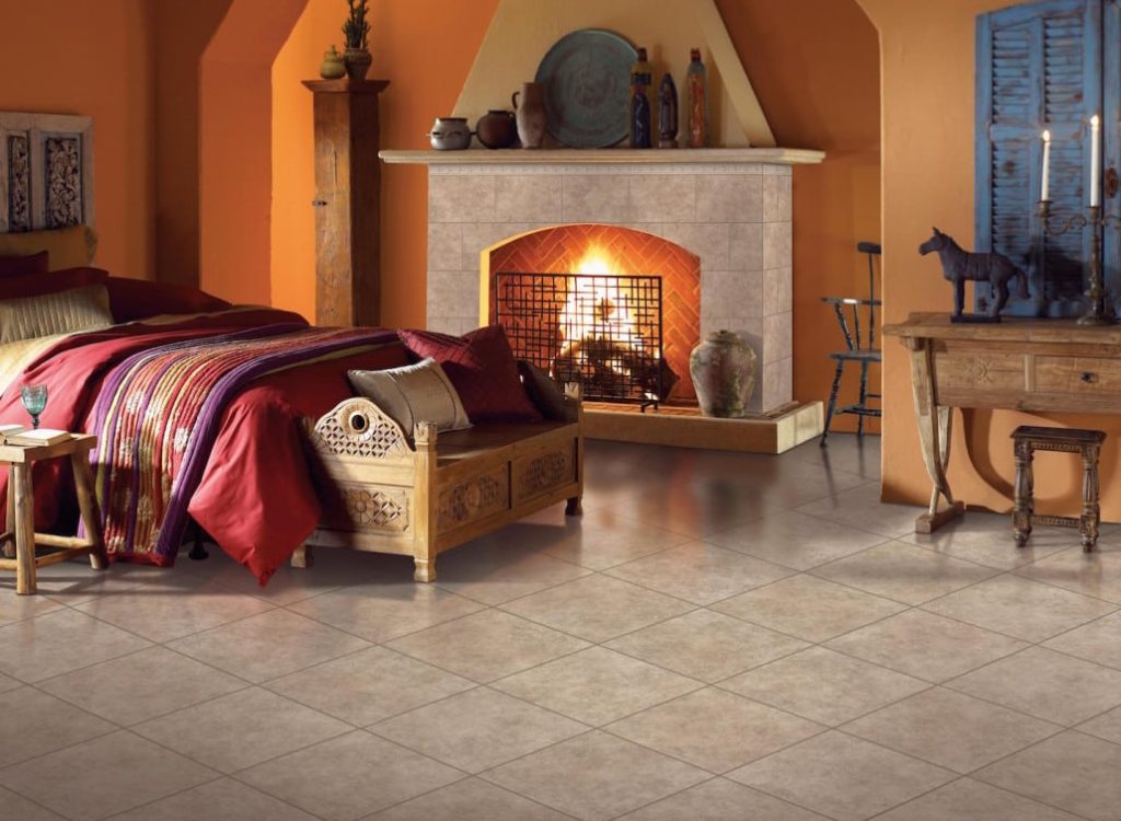 Tile 11 A warm bedroom features a bed with red bedding, a wooden bench, and a fireplace with a roaring fire.