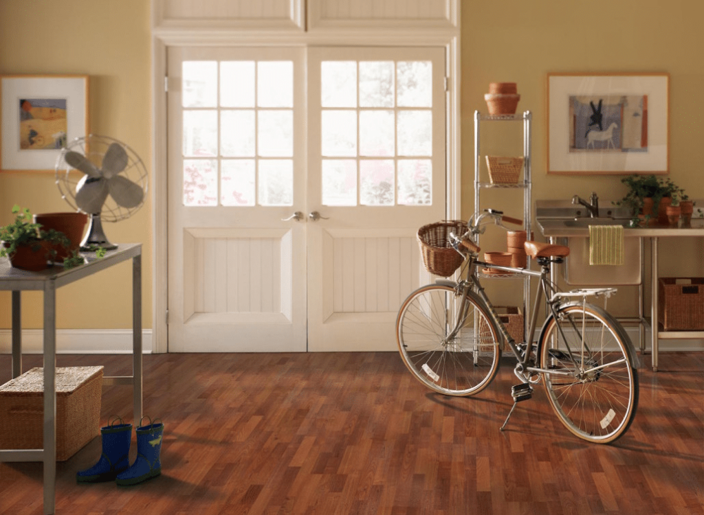 Laminate 11 A room with hardwood floors, white french doors, a fan, plants, a bicycle, and a utility sink.